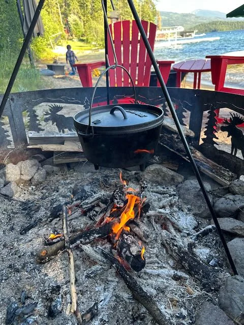 Dutch oven suspended over the outdoor fire with the lake beyond