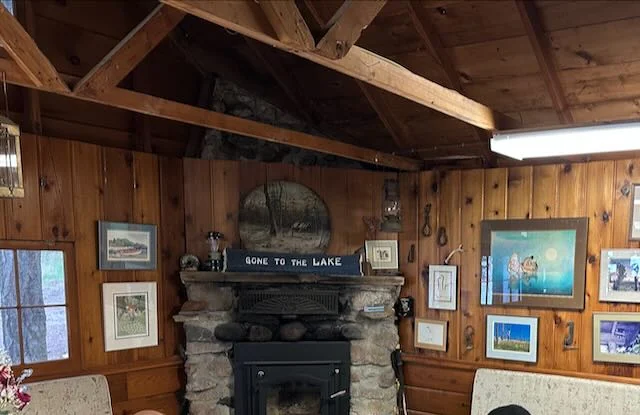 Wood-paneled living room with exposed beams and stone fireplace