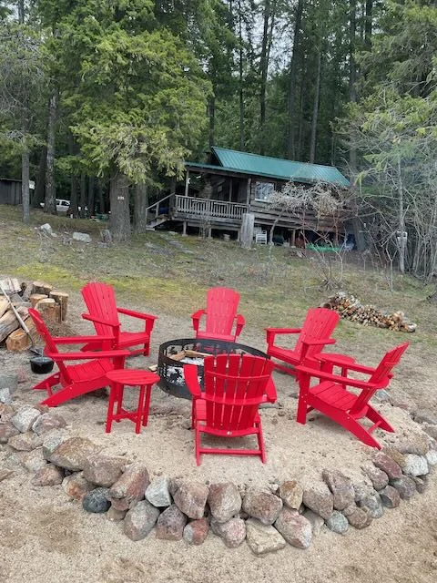 Historic cedar cabin above a stone-ringed lakeside fire pit