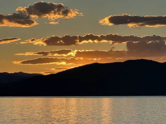 Golden sunset over Priest Lake and dark mountain silhouettes