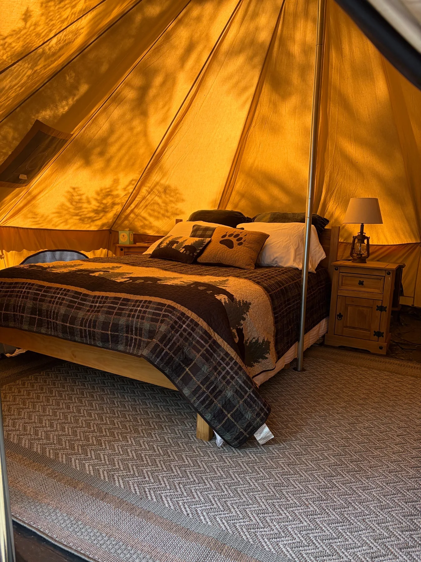 Warm interior of Huckleberry Retreat with queen bed, rustic nightstand and forest-themed bedding